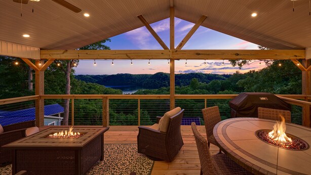 An outdoor deck with a fire pit, wicker furniture, and a view of a lake and forest. - Freshly Remodeled House! Overlooks Dale Hollow! (Byrdstown)
