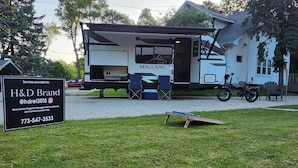 A mobile home with a covered porch, a motorcycle, and a sign for H&D Brand services. - Cozy RV Vacation (Antioch)