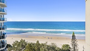 A beach view from a high-rise building with balconies overlooking the ocean.