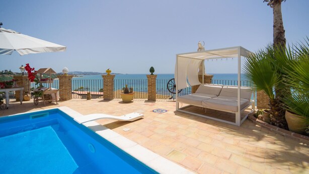 A poolside area with a bed, a table with flowers, and a view of the sea. - Stunning home in Ciotta with WiFi (Ciotta)