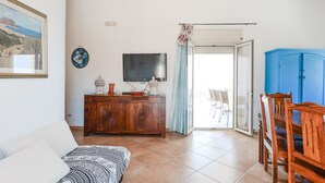 A living room with a sofa, a wooden cabinet, a television, and a dining area with chairs and a table. - Stunning home in Ciotta with WiFi (Ciotta)