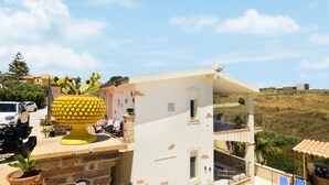 A white building with a balcony, a large yellow decorative object, and a white car parked nearby. - Stunning home in Ciotta with WiFi (Ciotta)