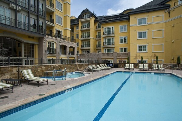 A swimming pool with lounge chairs and a stone wall. - Vail Ritz-carlton Residence Club 2 Bedroom Luxury Condo (Vail)
