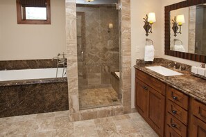 A bathroom with a glass-enclosed shower, a bathtub, and a vanity with a sink and mirror. - Vail Ritz-carlton Residence Club 2 Bedroom Luxury Condo (Vail)