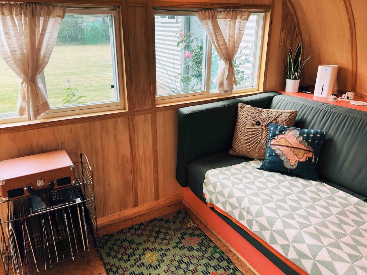Un intérieur chaleureux avec un canapé vert, des coussins à motifs, une petite table et une valise.