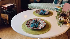 Una mesa de comedor con platos y cubiertos, una lámpara colgante y una cama con almohadas en una habitación con paredes de madera.