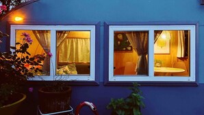 Una casa con dos ventanas, cada una con cortinas, y una escultura de flamenco rojo en el frente.