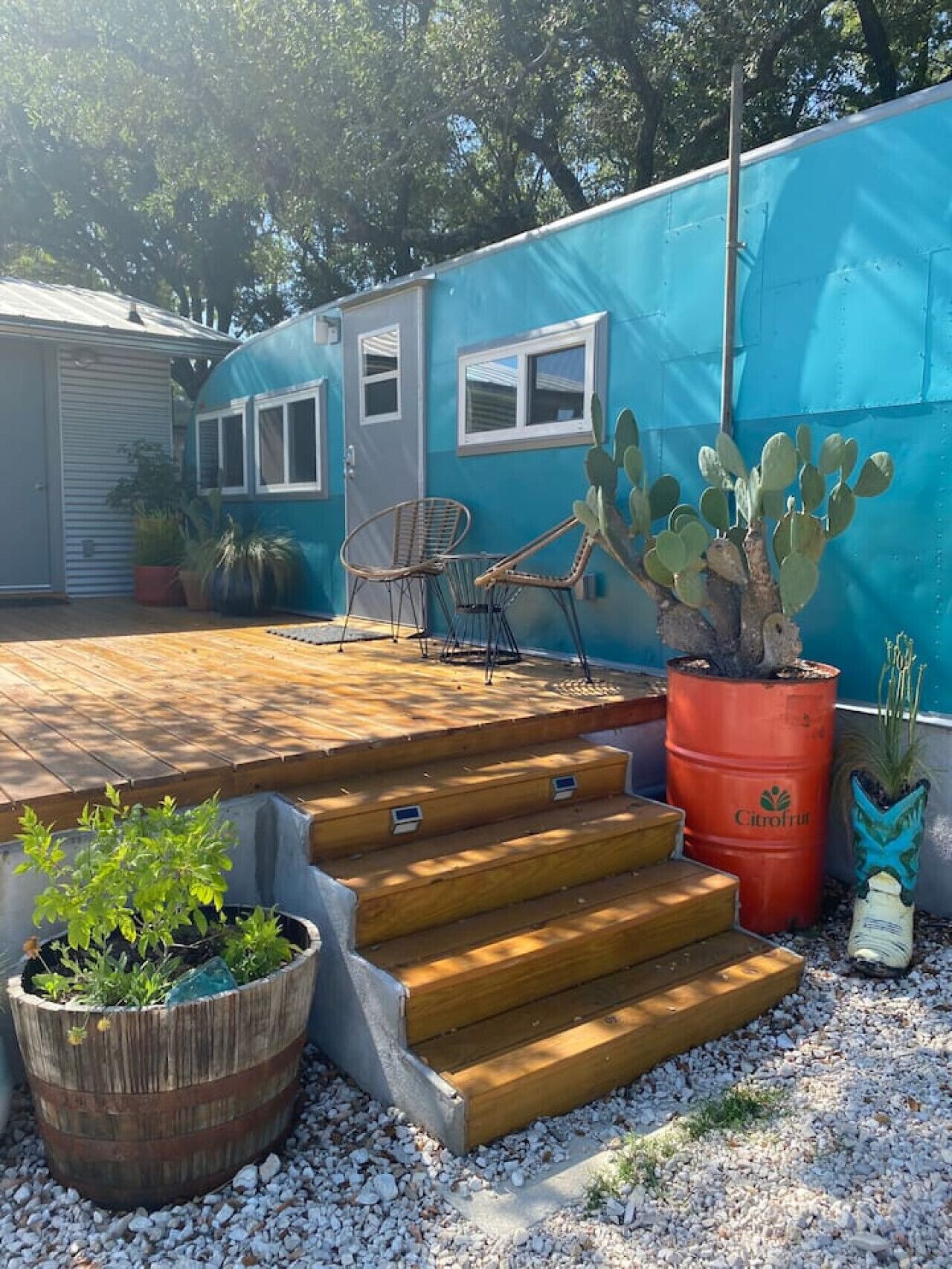 A blue house with a wooden deck, a cactus, and a chair.