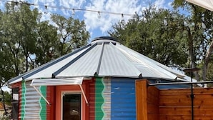 A small, single-story structure with a red door, a corrugated metal roof, and a wooden fence. - Silo house - 3 acres +pool +outdoor shower  “Opal” (Austin)