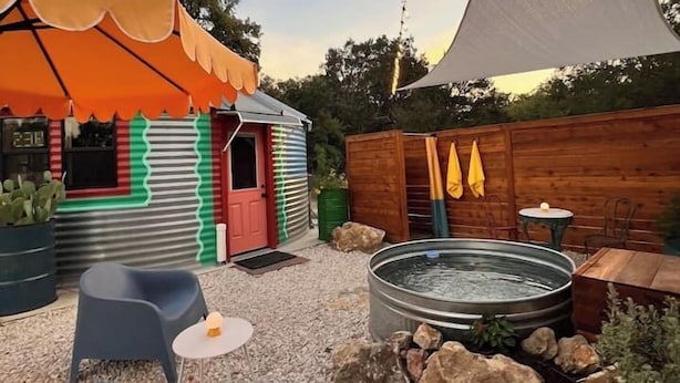 A patio area with a small building, outdoor seating, a hot tub, and a large shade sail. - Silo house - 3 acres +pool +outdoor shower  “Opal” (Austin)