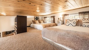 Ein Schlafzimmer mit Holzboden, einem Bett, einem Nachttisch und einem Fenster mit Vorhängen.