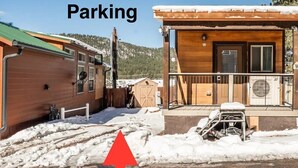 A cabin with a porch, a covered outdoor area, and a parking area indicated by an arrow.