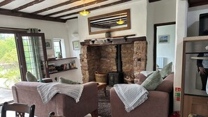 Un salon chaleureux avec une cheminée en pierre, des canapés confortables et un coin repas comprenant des chaises et une table en bois.