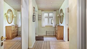 A hallway with wooden cabinets, a mirror, and a window with curtains. - Pet friendly home in Stege with WiFi (Stege)