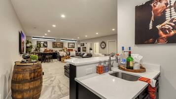 A modern kitchen with a bar area, a dining space, and a living room.
