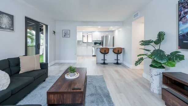 A modern living room with a dark sofa, a wooden coffee table, and a large plant.