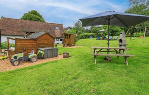A backyard with a wooden playhouse, a picnic table, a grill, and a tractor. - Stunning home in Alette with WiFi (Alette)