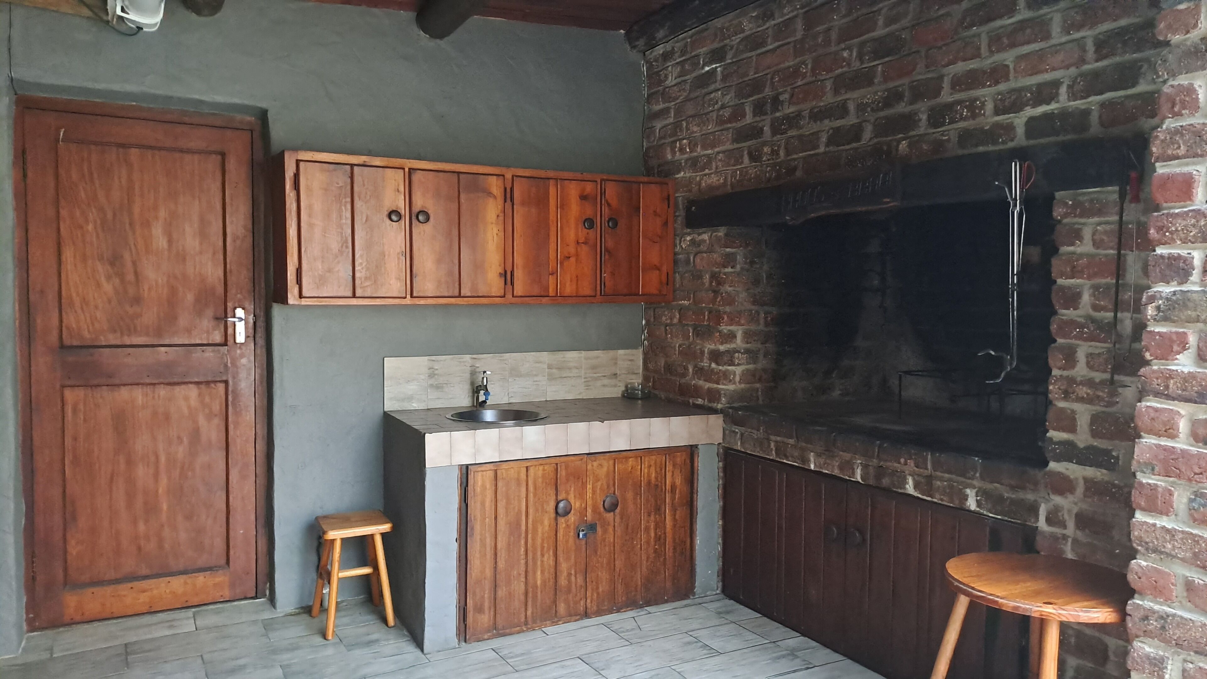 A kitchen with wooden cabinets, a sink, and a brick oven.
