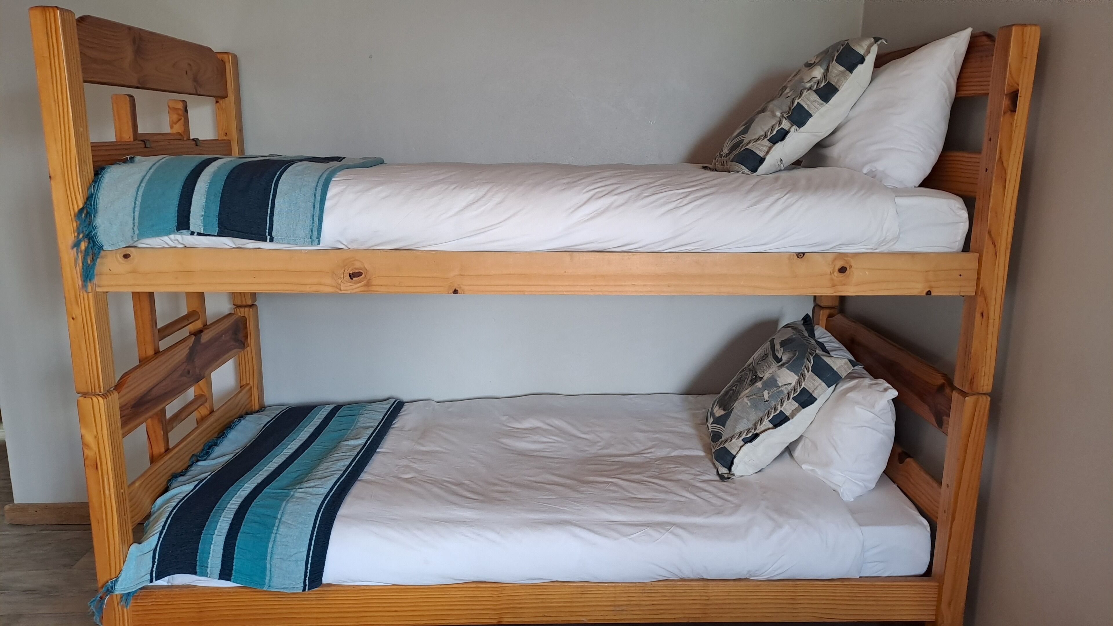 A bunk bed with two levels, each with a pillow and a striped blanket.