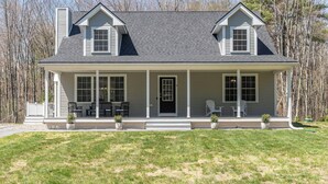 A two-story house with a covered porch, a chimney, and a front door. - Spacious Pet Friendly-Close to Beach and Town! (Kennebunk)