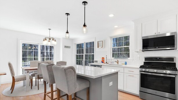 A modern kitchen with white cabinetry, a central island, stainless steel appliances, and pendant lighting. - Spacious Pet Friendly-Close to Beach and Town! (Kennebunk)