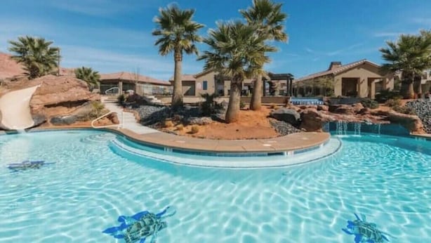 A swimming pool with a slide, palm trees, and houses in the background. - Paradise Village 55 with Pool Water Park & Hot Tub

 (Santa Clara)