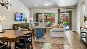 A modern living room with a wooden dining table, a blue armchair, and a grey sofa. - Paradise Village 55 with Pool Water Park & Hot Tub

 (Santa Clara)