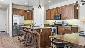 A modern kitchen with wooden cabinets, stainless steel appliances, and a central island with bar stools. - Paradise Village 55 with Pool Water Park & Hot Tub

 (Santa Clara)