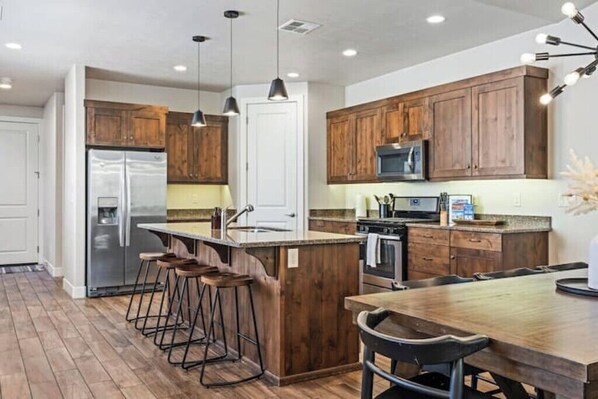 A modern kitchen with wooden cabinets, stainless steel appliances, and a central island with bar stools.