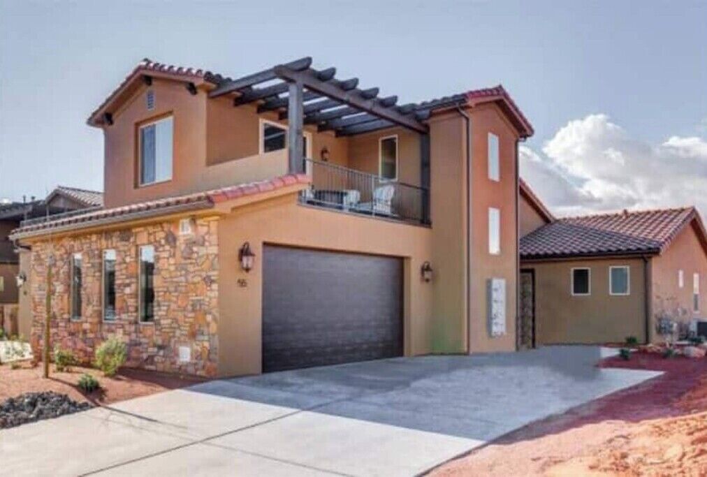 Una casa a due piani con facciata in pietra, un garage e un portico coperto.