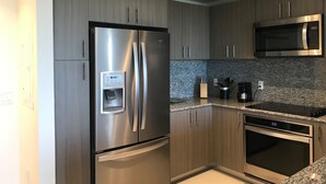 A modern kitchen with stainless steel appliances, granite countertops, and wooden cabinetry. - Modern building, centrally-located condo,2 bedrooms/2 bathrooms, parking space.  (Doral)