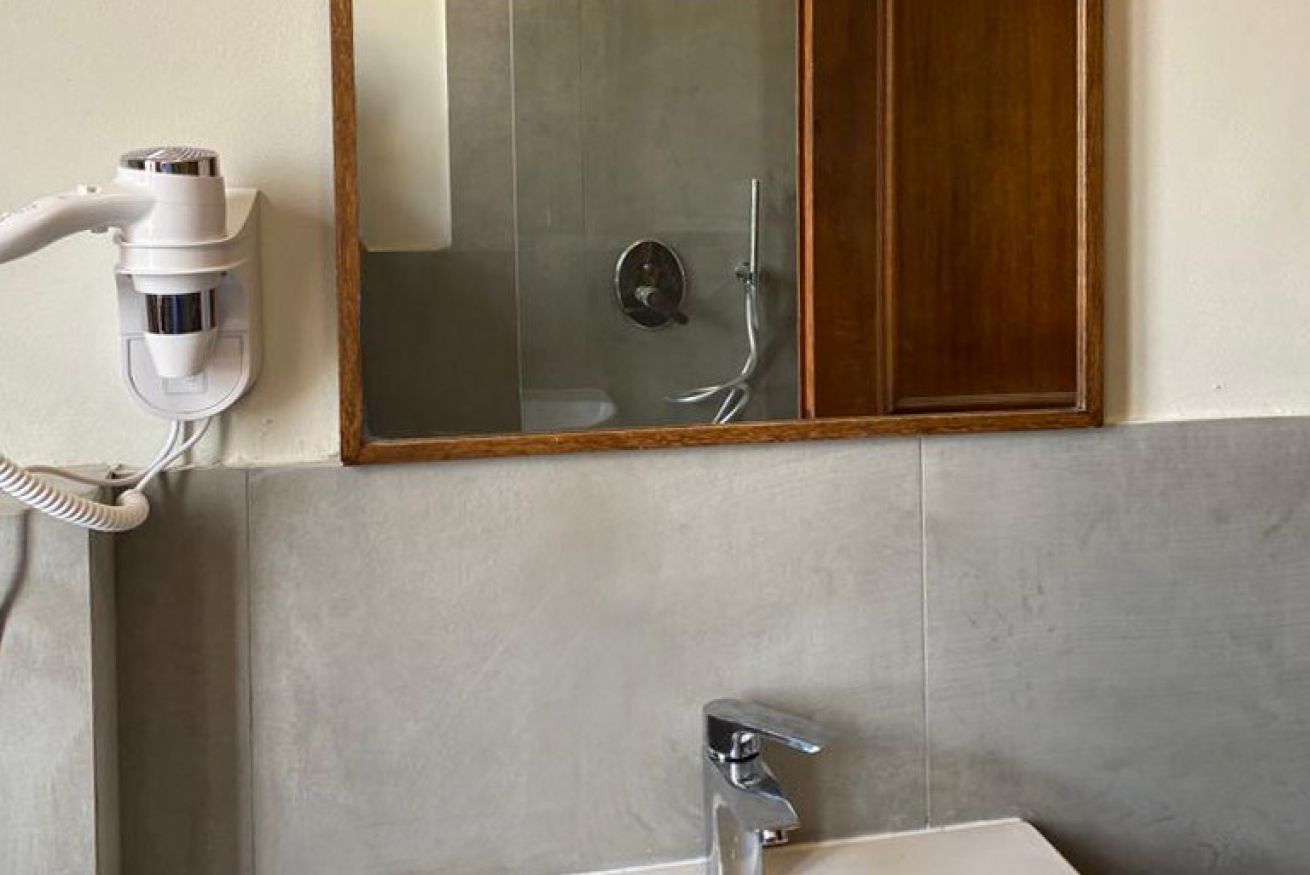 A bathroom with a hairdryer, a mirror, and a shower.