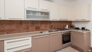 A modern kitchen with a built-in oven, a stainless steel sink, and a microwave.