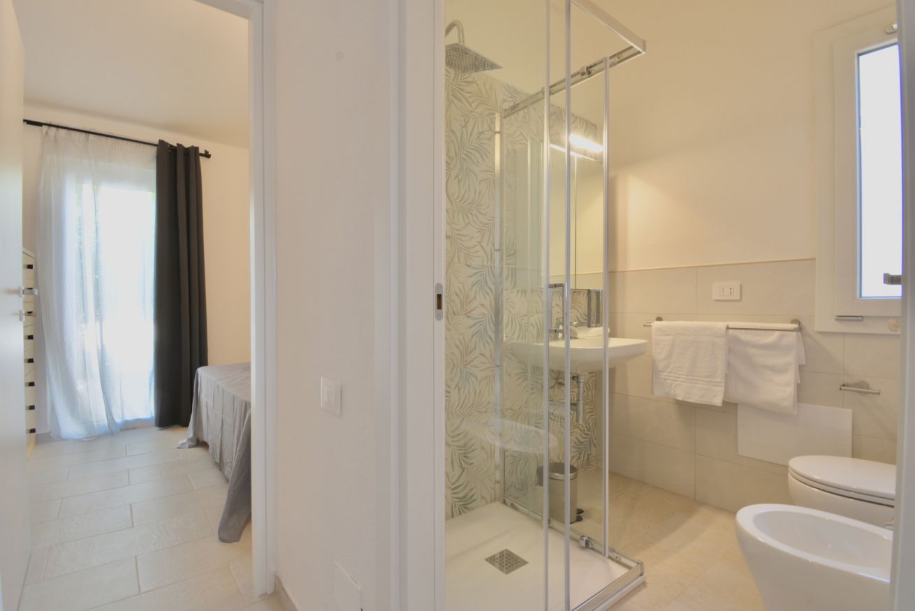 A modern bathroom with a glass shower enclosure, a white sink, and a toilet.