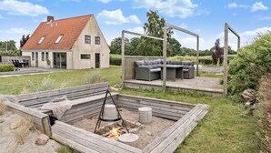Una casa moderna con tetto spiovente e una terrazza con mobili da esterno e un braciere.