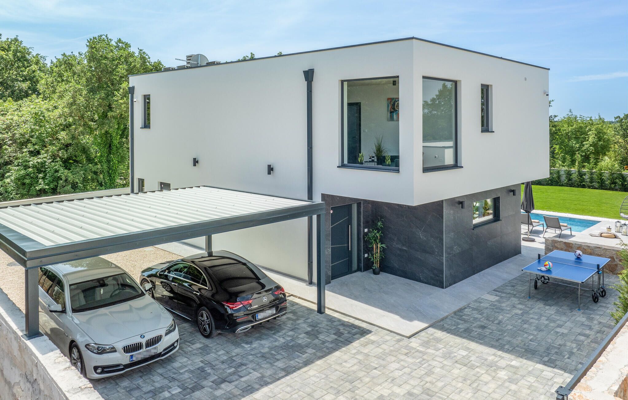 A modern two-story house with a covered garage, a swimming pool, and outdoor seating.
