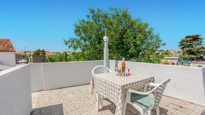 A terrace with a checkered table and chairs, a bottle, and a glass on the table. - 2 bedroom cozy apartment in Nin (Nin)