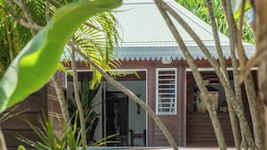 Una casa di legno con un portico, immersa nella vegetazione tropicale.