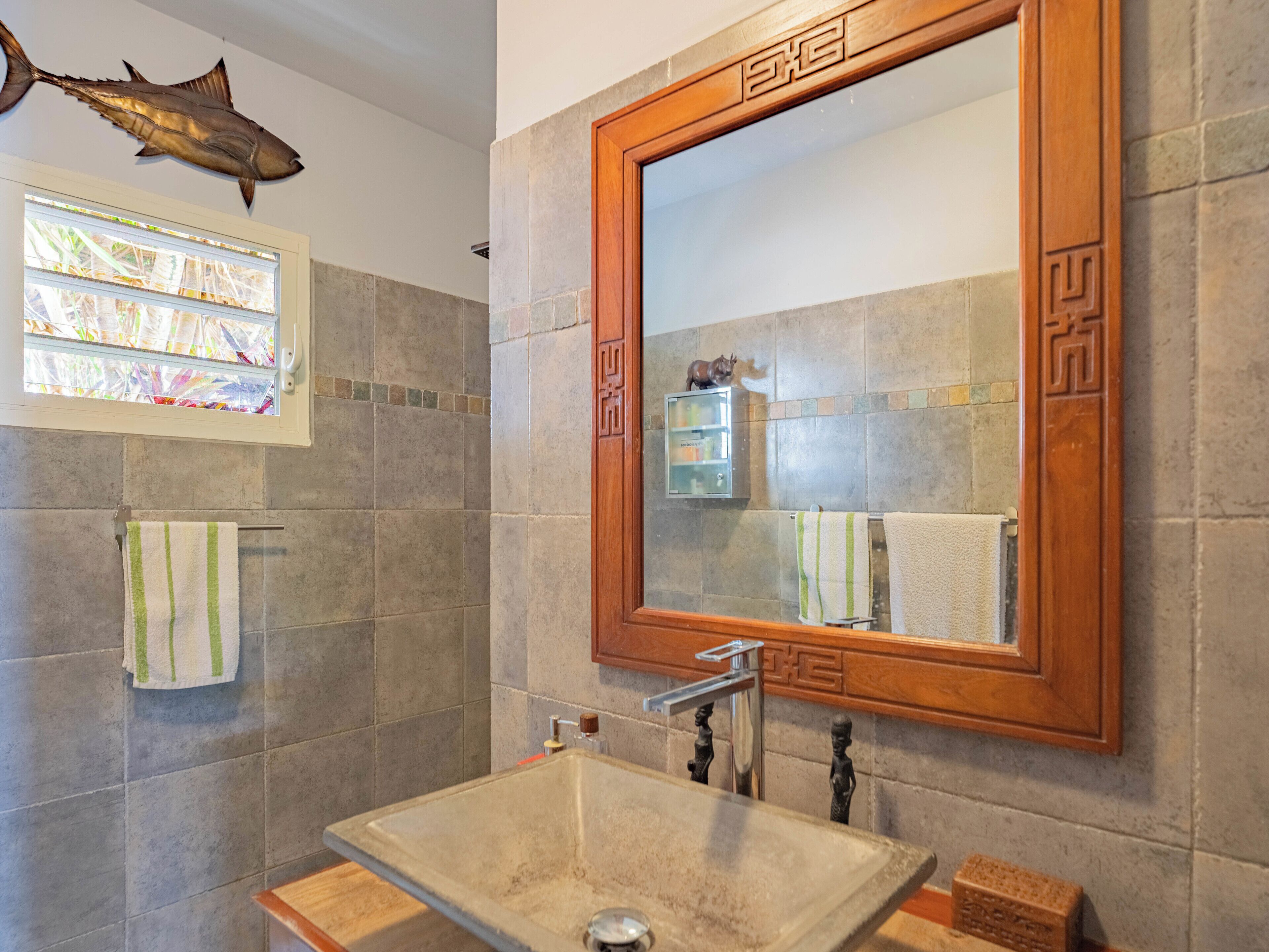 A bathroom with a large mirror, a stone sink, and a shower.