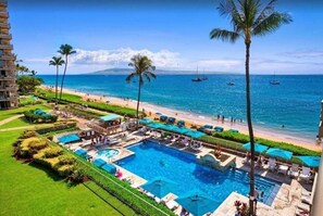 Un complexe hôtelier doté d’une grande piscine, d’un accès à la plage et de palmiers.
