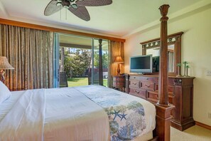 Une chambre à coucher comprenant un lit, une télévision, une commode et une grande fenêtre avec des rideaux.