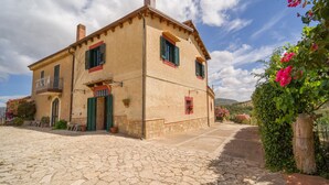 A two-story stone building with a cobblestone courtyard, green shutters, and a balcony with a metal railing. - Awesome home in Palazzo Adriano (Palazzo Adriano)