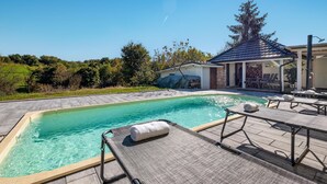 A swimming pool with lounge chairs and a covered patio area.