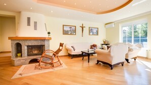 A spacious living room with a fireplace, comfortable seating, and artwork on the walls.