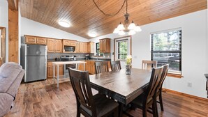 Una cocina moderna con armarios de madera, un refrigerador de acero inoxidable y un comedor con mesa y sillas de madera.