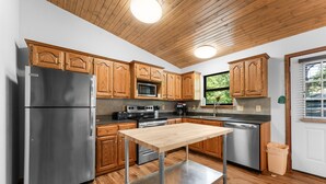 Una cocina moderna con armarios de madera, electrodomésticos de acero inoxidable y una mesa de madera.