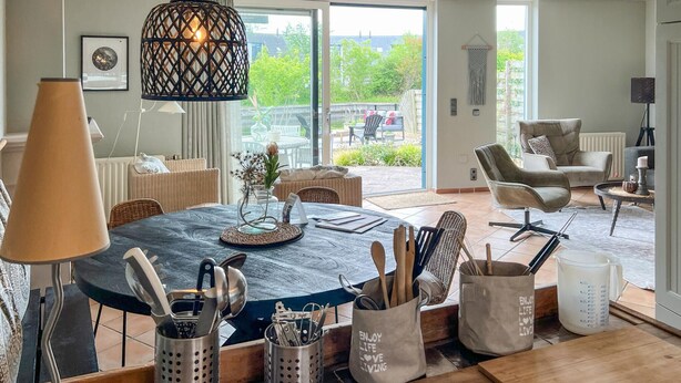 A dining area with a round table, chairs, and a hanging light fixture.