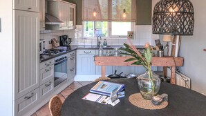 A kitchen with grey cabinets, a stove, and a dining table with brochures and a vase.