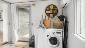 A laundry room with a washing machine, a drying rack, a basket, and a shelf with cleaning supplies. - 2 bedroom stunning home in Væggerløse (Væggerløse)