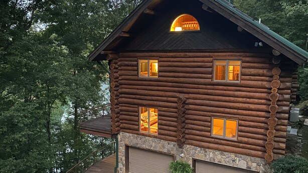 A log cabin with a stone foundation, multiple windows, and a garage. - The Cabin on Fontana Lake
Lake Front Paradise in the Smokies (Robbinsville)